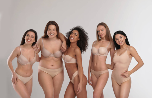 Group of women with different body types in underwear on light background - Фото, изображение