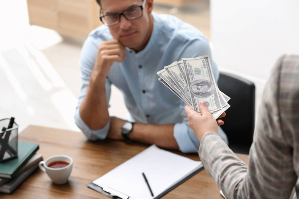 Woman offering bribe money to man at table, closeup - Zdjęcie, obraz