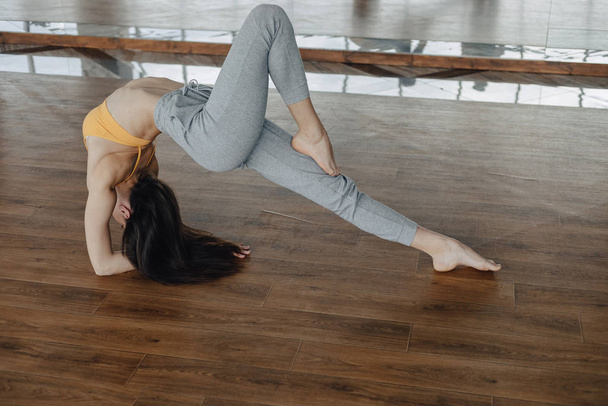 mladá přitažlivá dívka na dřevěné podlaze, která dělá jóga, protahuje a relaxuje - Fotografie, Obrázek
