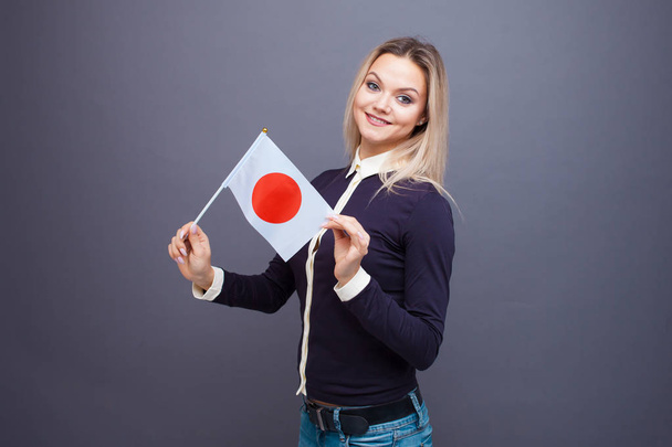 Immigration and the study of foreign languages, concept. A young smiling woman with a Japan flag in her hand. - Fotografie, Obrázek