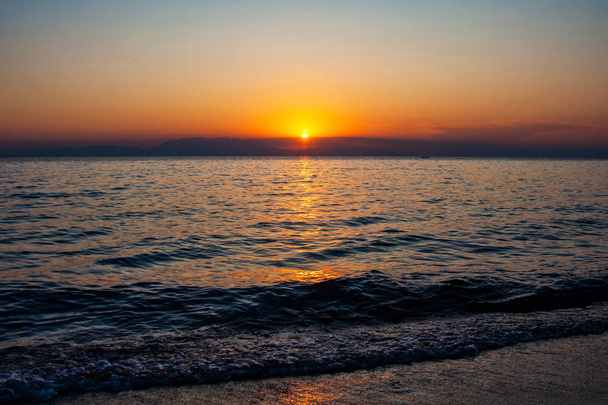海と山の上に劇的な夕日。ハルキディキギリシャのピルゴス・サニで撮影. - 写真・画像