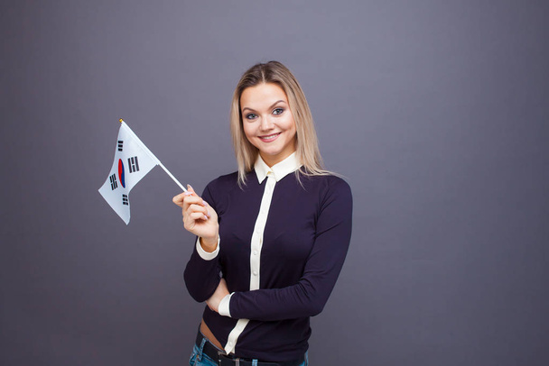 Immigration and the study of foreign languages, concept. A young smiling woman with a Republic of Korea flag - 写真・画像