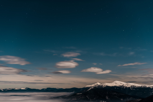 夕方には白いふわふわの雲に覆われた雪山の景色 - 写真・画像
