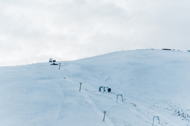 мальовничий вид на засніжену гору з підйомником гондоли та білими пухнастими хмарами вище
 - Фото, зображення