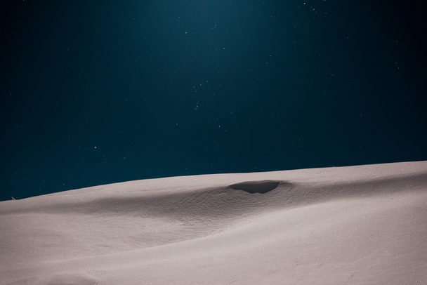 schilderachtig uitzicht op de berg bedekt met pure witte sneeuw tegen de nacht sterrenhemel - Foto, afbeelding