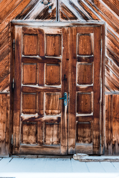 houten deur in verweerd ruw huis met pure sneeuw - Foto, afbeelding