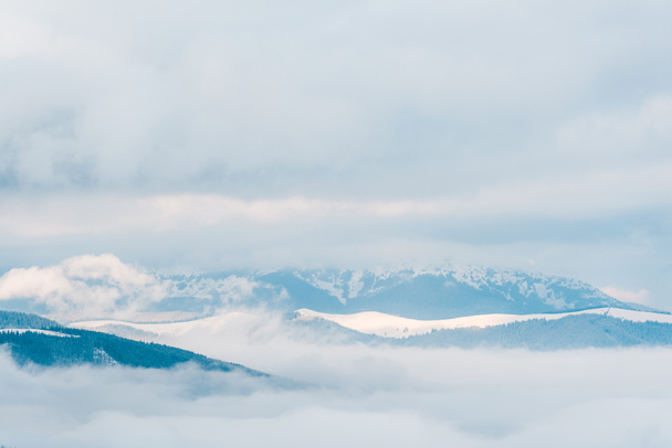 vista panorámica de las montañas nevadas en las nubes esponjosas blancas
 - Foto, Imagen