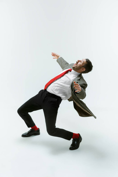 Young caucasian man moving flexible on white studio background - Фото, зображення