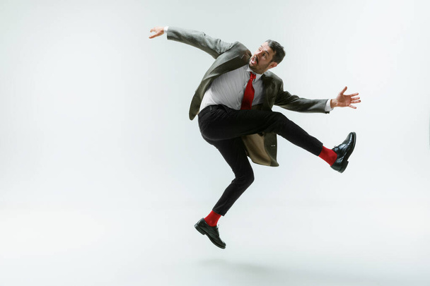Young caucasian man moving flexible on white studio background - 写真・画像