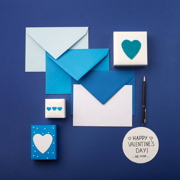 Μπλε φάκελοι, δώρα και λευκές καρδιές σε κλασικό μπλε  - Φωτογραφία, εικόνα