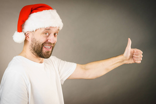 Man in santa claus hat giving thumb up - Photo, Image