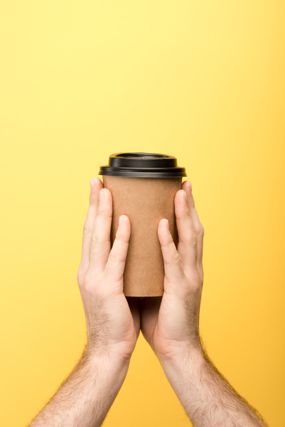 cropped view of man holding paper cup on yellow background  - Photo, Image