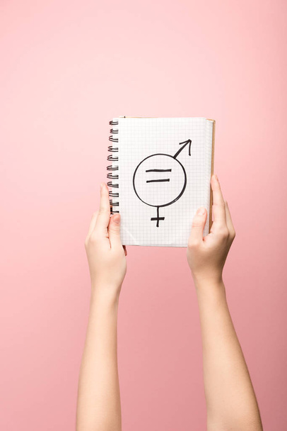 cropped view of woman holding notebook with male and female sign on pink background  - Фото, зображення