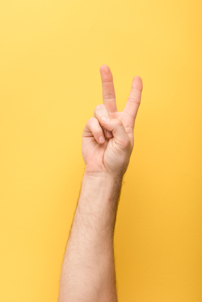 vista recortada del hombre mostrando gesto de paz sobre fondo amarillo
  - Foto, imagen