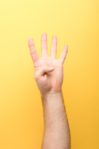 cropped view of man showing four fingers on yellow background  - Foto, Imagem