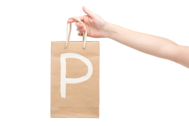 白い文字で孤立したp文字でショッピングバッグを保持する女性のクロップドビュー  - 写真・画像