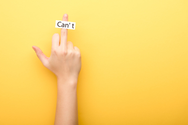 cropped view of woman showing middle finger and card with cant lettering on yellow background  - 写真・画像