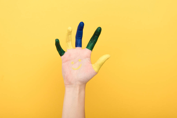 abgeschnittene Ansicht einer Frau mit bunten Fingern, die Handfläche isoliert auf gelb zeigt - Foto, Bild