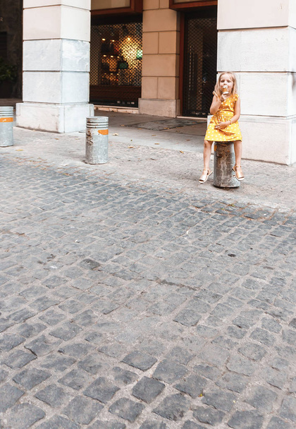 милая маленькая девочка ест мороженое на улице - Фото, изображение