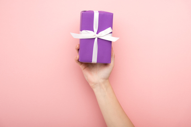 cropped view of woman holding gift on pink background  - Фото, зображення
