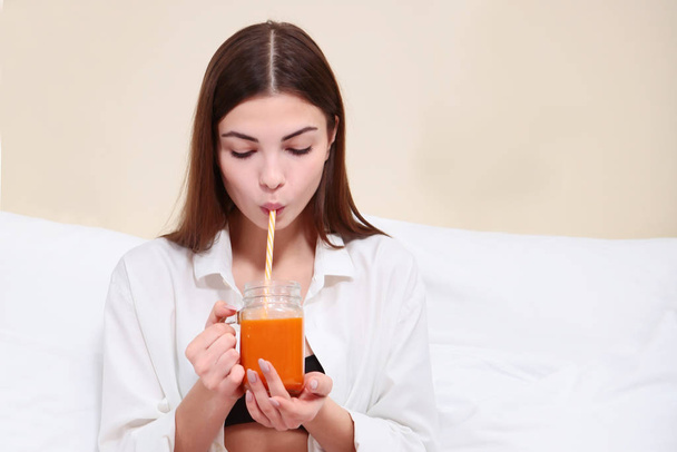 Beautiful girl drinking juice in bed. Breakfast concept at home or in the hotel. - Φωτογραφία, εικόνα