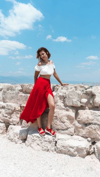 young pretty girl with curly hair wearing fashionable clothes posing on stone background in summer day, copy space. - Φωτογραφία, εικόνα