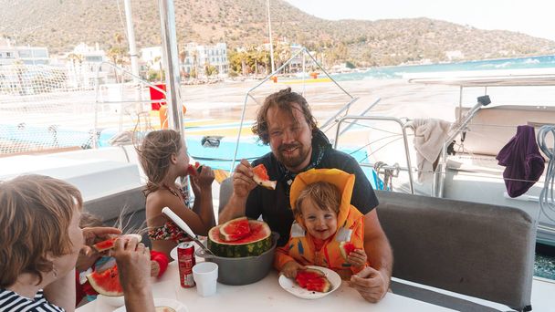 dad eating pizza with kids the beach - Foto, afbeelding