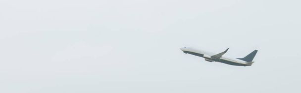 Low angle view of airplane in cloudy sky, panoramic shot - Фото, изображение
