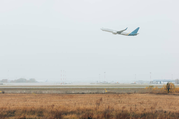 Airplane departure in cloudy sky above airfield with runway - Фото, изображение