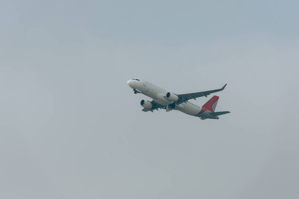 Low angle view of jet plane in cloudy sky - Zdjęcie, obraz