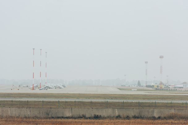 Aviones en la pista del aeropuerto con cielo nublado al fondo
 - Foto, Imagen