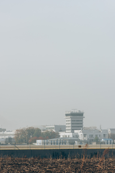 Edificios aeroportuarios con pista de aterrizaje y cielo nublado
 - Foto, Imagen
