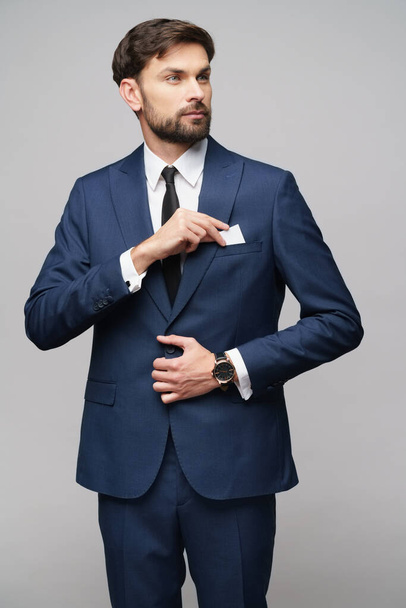 studio photo of young handsome businessman wearing suit holding business card - Foto, Imagem