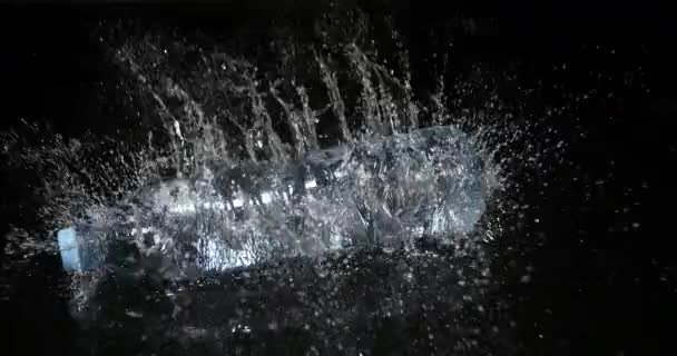 Láhev vody padající na vodu proti černému pozadí, zpomalení 4k - Záběry, video