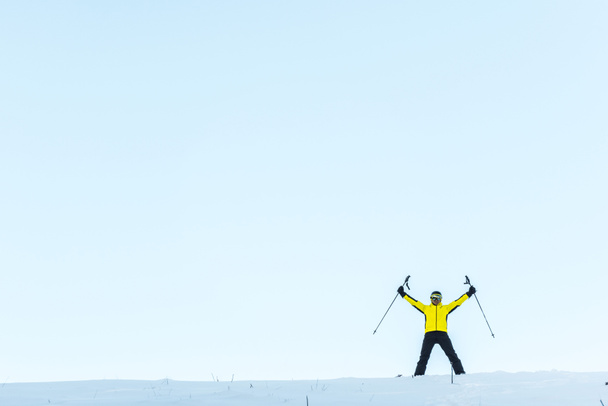 lyžař v helmě drží hole, zatímco stojí na sněhu  - Fotografie, Obrázek