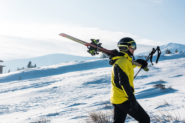 vista lateral del esquiador caminando con palos en las montañas
  - Foto, Imagen