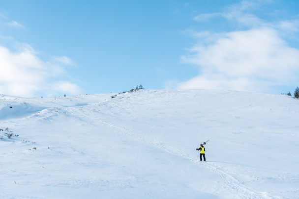 αθλητής στο κράνος περπάτημα με μπαστούνια του σκι σε λευκό χιόνι στα βουνά  - Φωτογραφία, εικόνα