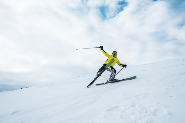 Aufgeregter Sportler hält Skistöcke in der Hand und fährt auf weißer Piste - Foto, Bild
