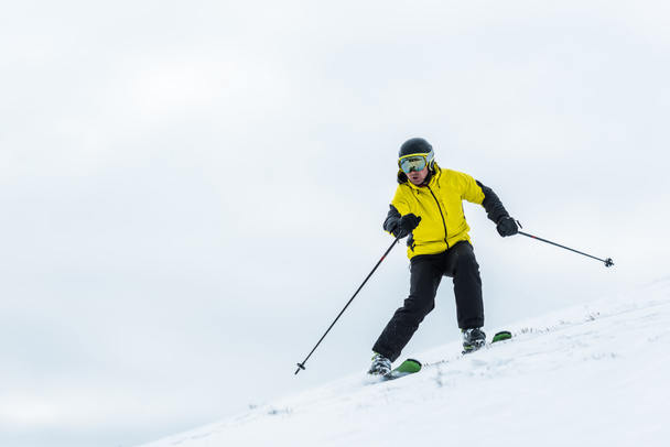 esquiador en casco sosteniendo palos y esquiando en pista en invierno
  - Foto, Imagen