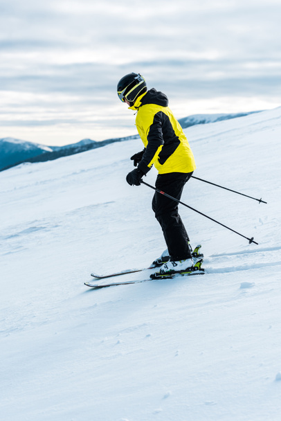 skier in helmet holding sticks and skiing on slope outside  - Fotó, kép