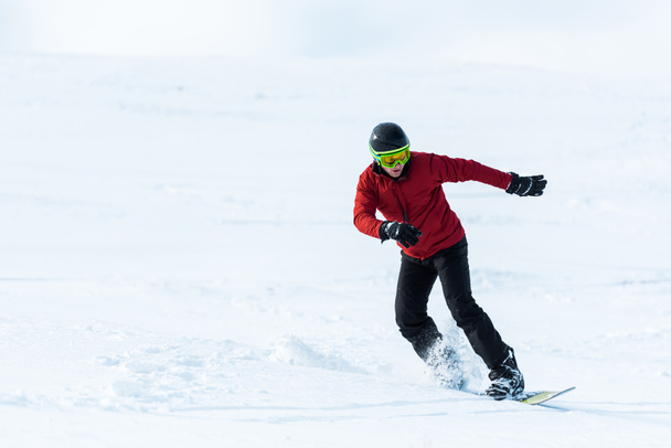 snowboarder atletico in casco e occhialini gesticolando mentre si pedala sul pendio esterno
  - Foto, immagini