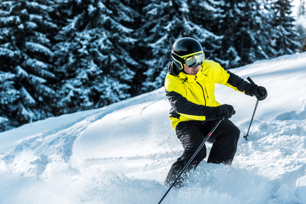 лыжник в очках и шлеме, держащий лыжные палочки и катающийся на лыжах возле гор
  - Фото, изображение