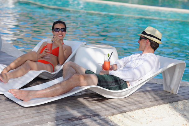Young couple relax and take fresh drinks at poolside - Zdjęcie, obraz