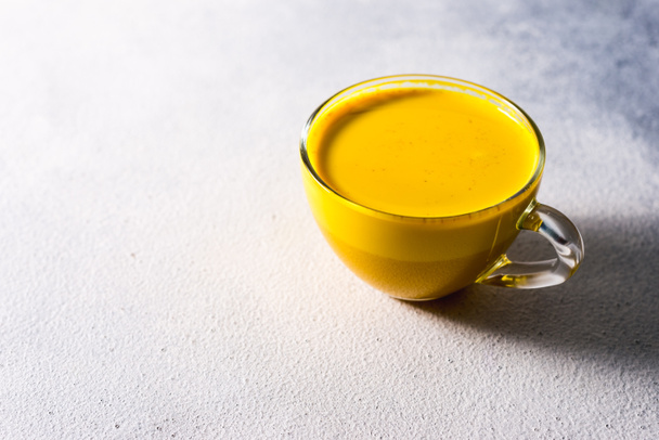 Golden turmeric milk on the white background with spices cinnamon and ingredients - Photo, Image