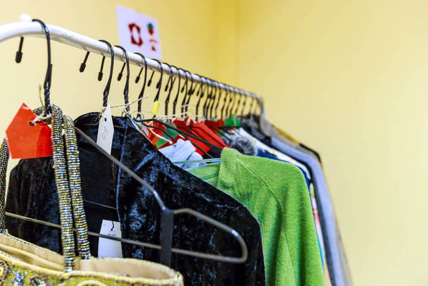 Een stand met tweedehands kleding op hangers - Foto, afbeelding