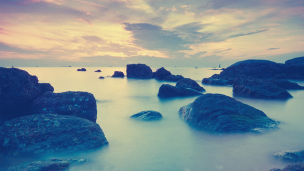 Вінтажний морський пейзаж з драматичною хвилею і камінням на заході сонця
. - Фото, зображення
