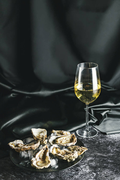 Opened oysters and white wine on stone table. - Foto, Imagen