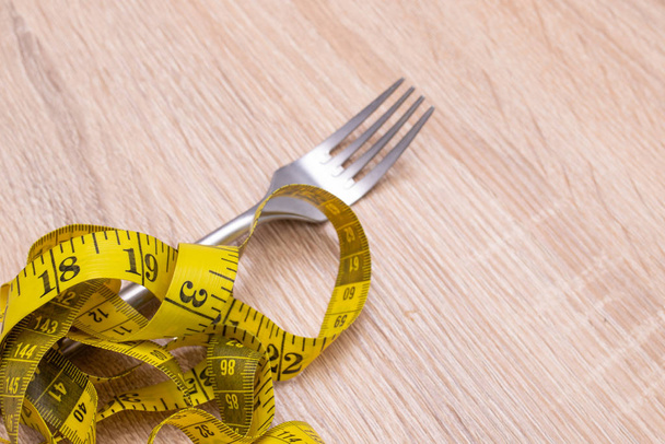 fork with tape measure, diet and weight loss concept - Foto, afbeelding