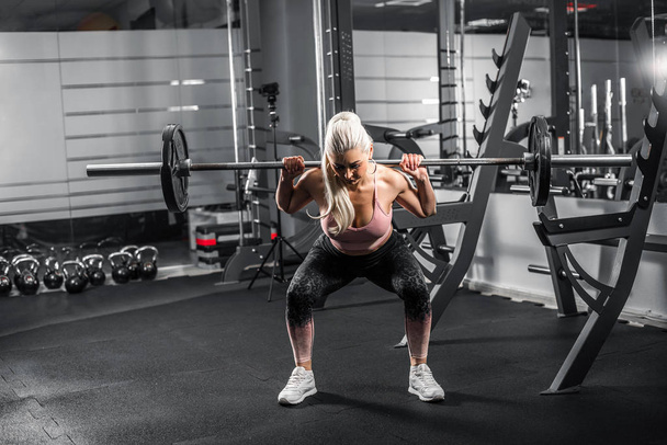 Blonde doing squats in modern gym. - Photo, Image