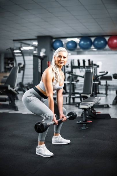 Blonde doing bent over barbell row exercise in gym. - Valokuva, kuva